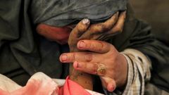 La palestina Buthayna Abu Jazar llora mientras sujeta la mano de su hijo Hazma, muerto en un ataque israelí, el jueves en Rafah.