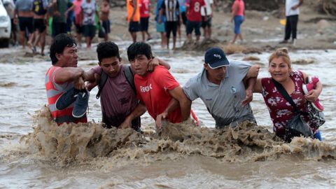 Algunas de las v�ctimas de las crecidas provocadas por �El Ni�o� tratan de cruzar el r�o Vir�, en Per�, tras caer derribado el puente