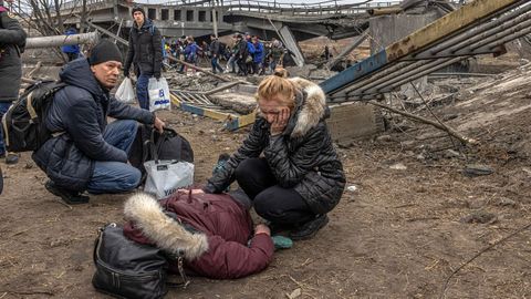 Una mujer llora junto a una mujer tendida despus de cruzar un puente destrozado en la ciudad de Irpn, cerca de Kiev