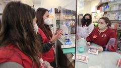 Laura y Natalia, de Cruz Roja, explican en una farmacia el programa y piden la colaboraci�n de los farmac�uticos
