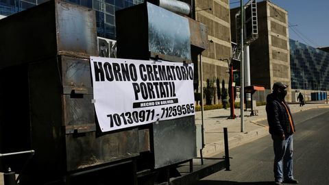 Un hombre se encuentra cerca del prototipo de un crematorio mvil con una pancarta que dice  Crematorio mvil, hecho en Bolivia , construido por un ingeniero local para aliviar la acumulacin de cadveres en los crematorios locales, en La Paz, Bolivia