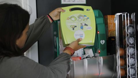 Una empleada de la gasolinera mostrando el desfibrilador adquirido por la empresa para ponerlo a disposición del municipio.