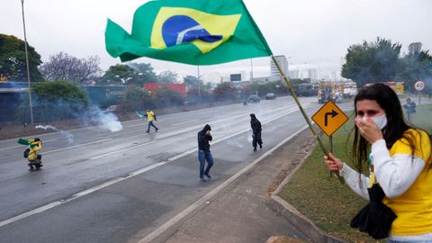 Seguidores del derrotado Bolsonaro huyen de los botes de humo en una protesta en la ciudad brasilea de Barueri.