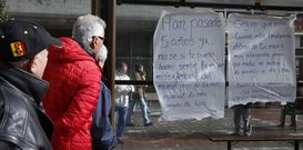 Vecinos de los Castros leen el mensaje que apareci� ayer pegado en la parada del bus. 