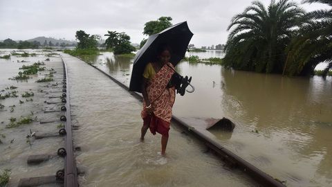 Un aldeano indio camina a lo largo de una v�a de ferrocarril sumergida por las inundaciones en Koliabor, India