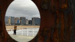 Una pareja se hace una foto frente a la playa de San Lorenzo de Gijn