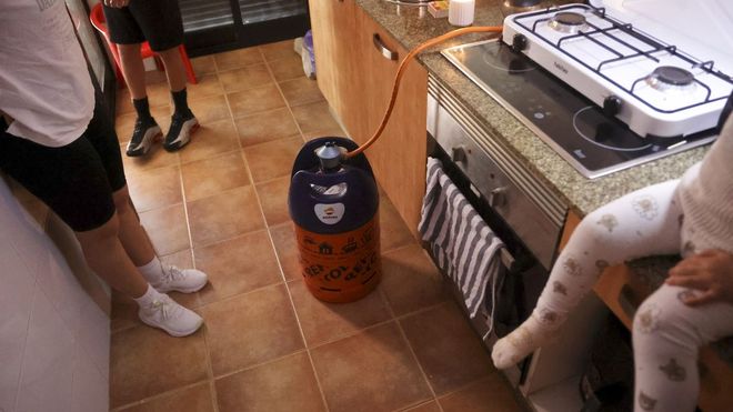 La vecina y sus hijos, los dos menores, en la cocina, con bombonas para calentar agua y poder cocinar
