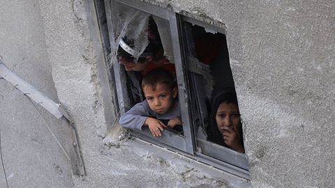 Un ni�o y una mujer miran por la ventana en una vivienda de la ciudad de Gaza