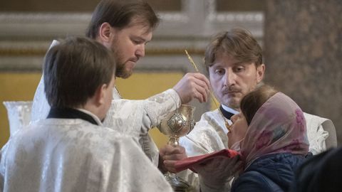 Los fieles reciben la comunión a través de una cuchara en una iglesia de San Petersburgo, a pesar de que se han establecido normas para garantizar la higiene
