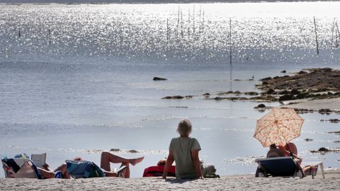 Personas tomando sol en la playa.