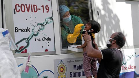 Una nia reacciona cuando un funcionario de salud usa un hisopo para obtener la muestra en una aldea durante el toque de queda, en Colombo, Sri Lanka