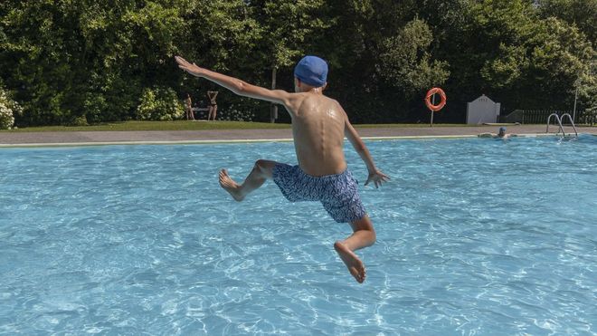 En foto de archivo, un joven se divierte saltando en una piscina.