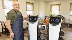 V�ctor Manuel Su�rez posa en su local con los dos robots, a los que llama Lupita y Pirlo.