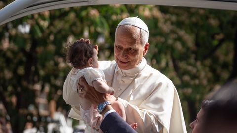 El papa Le�n XIV bendice un beb� en el papam�vil de camino al Movistar Arena.