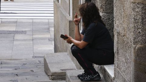 Una mujer fumando en una calle de una localidad gallega, en una imagen de archivo