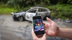 En el m�vil se puede ver la imagen del incendio que destruy� el coche del fondo en Mollavao