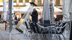 Un trabajador recoge el mobiliario de la terraza de un restaurante en el centro de C�rdoba