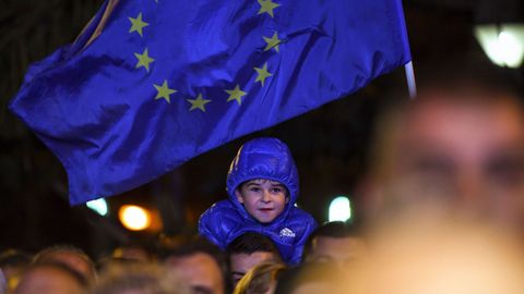Un ni�o peque�o sonr�e bajo una bandera de la Uni�n Europea.
