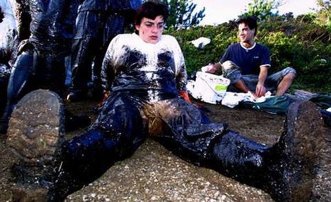 Un voluntario descansa tras retirar fuel en la costa de O Grove en diciembre del 2002.