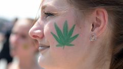 Una mujer lleva pintada en su cara la hoja de marihuana.
