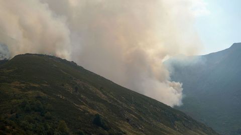 Miembros de la BRIF avanzan por una pista forestal cerca al incendio este jueves, en las cercanas de Genestoso (Cangas del Narcea), mientras un incendio afecta a la zona