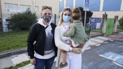 La ni�a protagonista del suceso, en brazos de su madre y con su t�a al lado, posa delante del colegio