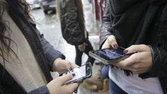 Un grupo de menores emplean sus tel�fonos m�viles durante el recreo de su instituto