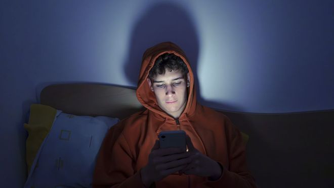Joven usando el m�vil en su cama