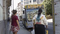 Usuarios del servicio de bus urbano de Santiago esperan en la parada de la plaza de Galicia