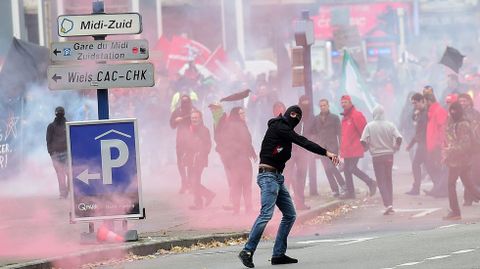 Un manifestante lanza un objeto durante los choques con la Polica en Bruselas, donde protestan por las medidas de austeridad del Gobierno.