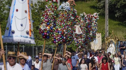 Estandartes y ramos con bolas de colores acompañan a la virgen en la procesión.