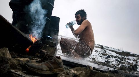 Un refugiado se lava fuera de un almac�n abandonado usado como refugio cerca de la estaci�n principal de tren de Belgrado (Serbia), donde se registran temperaturas bajo cero. Se calcula que alrededor de 7.000 refugiados est�n varados en Serbia.