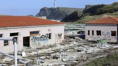 Las ruinosas instalaciones de la antigua planta de acuicultura, con el faro de Meir&aacute;s al fondo