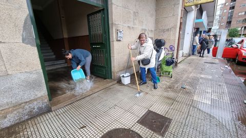 Vecinos de la calle Fernando Olmedo, en Pontevedra, se afanan en limpiar los restos del temporal de lluvia que inund�  garajes y bajos esta pasada noche