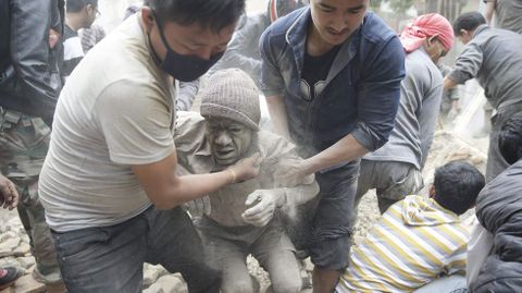 Dos hombres tratan de liberar a un hombre tras un derrumbe en Katmand.