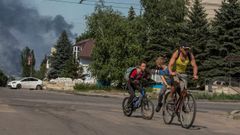 Un hombre y dos ni�os huyen en bicicleta de los bombardeos rusos en la localidad de Lisichansk, en la regi�n de Lugansk