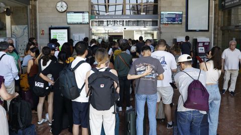 Personas miran las pantallas de la estaci�n de tren de Ourense para comprobar el cambio de horarios.