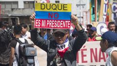 Un manifestante muestra un cartel contra el presidente Duque en una calle de Bogot