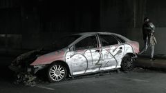 Coche calcinado y grafiteado bajo el viaducto de la calle Posse