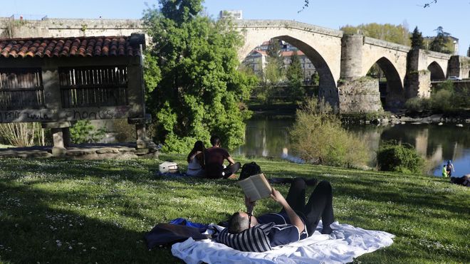 Un hombre reposa junto al Puente Viejo de Ourense este lunes.