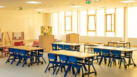 Nuevas aulas multifuncionales con sillas de colores y mesas plegables con ruedas, junto a mobiliario antiguo al fondo de la clase