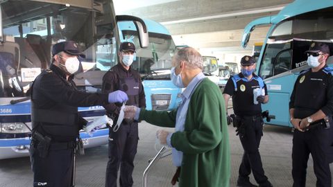 Agentes de la polica repartiendo mascarillas en la estacin de autobuses de Ferrol