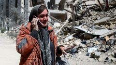 Una mujer habla por tel�fono junto a un edificio residencial destruido en Teher�n.