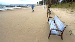 Un paseante caminaba ayer por el paseo de Samil completamente cubierto de arena por el viento.