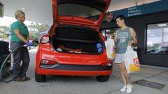Una mujer aprovecha el repostaje de su coche para realizar unas compras en la tienda de la gasolinera.