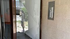 Cristal roto en el portal del edificio afectado