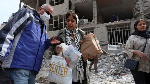 Civiles recogen las pertenencias que les quedan entre los escombros en Teher�n.