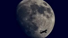 Un avi�n vuela con la luna creciente de fondo en Alemania.