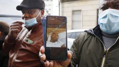 Dos amigos de Michael, tripulante del pesquero gallego, muestran su fotografa.