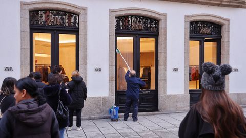 Un cristalero ultima la limpieza de las puertas del Zara de la calle Compostela antes de abrir las puertas en el primer d�a de rebajas